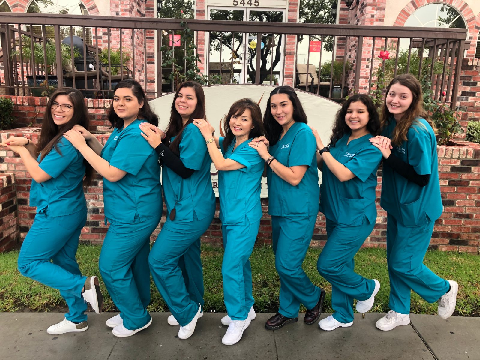 Trinity students in blue scrubs standing together outdoors